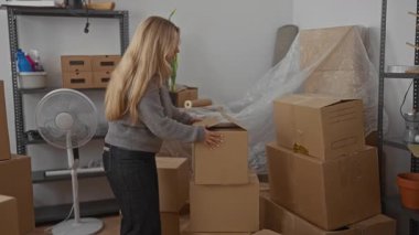 Yeni bir apartman dairesinde, içinde yelpaze ve raflar olan kutular düzenleyen bir kadın yakın zamanda taşınma deneyimini gösteriyor. Kapalı alandaki aktiviteler ve genç sarışınla taşınma sahneleri.