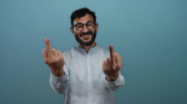 Mavi arka plana karşı el hareketleriyle hoşnutsuzluğunu ifade eden bir adam gözlük ve gömlek takarak gülümserken oyuncu bir senaryoda meydan okuma ve mizahı simgeliyor.