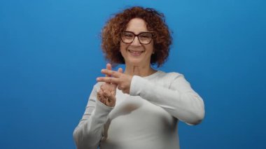 Beyaz gömlekli, kıvırcık saçlı, mavi arka planda etiket işareti olan bir kadın iletişim ve ifade öneriyor..