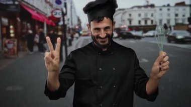 Açık havada gülümseyen İspanyol şef elinde çırpı çırpıcı, siyah üniformalı aşçılık mesleği..