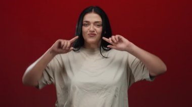 İzole edilmiş kırmızı bir arkaplanda poz veren genç bir kadın kıvrımlı ve büyük beden modasını neşeli bir ifadeyle vurguluyor..