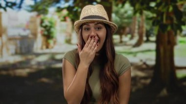 Uzun saçlı İspanyol kadın güneşli bir açık hava parkında gülümsüyor..