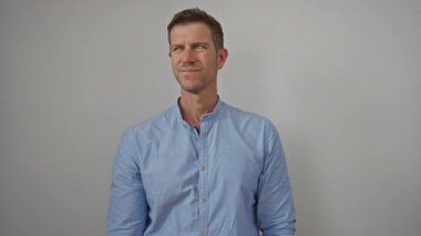 Genç bir adam, beyaz bir arka plana karşı hayal kırıklığını ifade eden elleriyle kulaklarını kapatıyor..