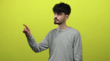 Gri kazaklı genç İspanyol adam izole edilmiş sarı arka planda odaklanma ve dikkat kavramı gösteriyor.