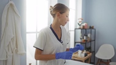 Klinikte eldiven ve üniforma giyen bir kadın, temiz, modern bir iç mekan ve profesyonel bir ortamda organize edilmiş raflarla çevrili tıbbi ekipmanlar hazırlıyor..