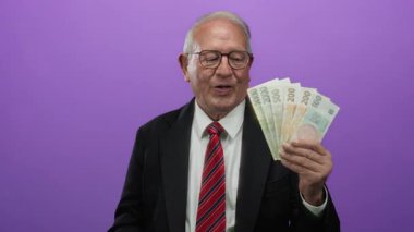 Takım elbiseli üst düzey bir adam elinde Czech Koruna banknotlarını mor arka planda tutuyor..