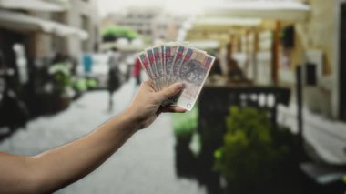 Şehir caddesindeki terasta, arka planda restoranı olan bir adam, canlı bir açık hava sahnesini çekiyor..