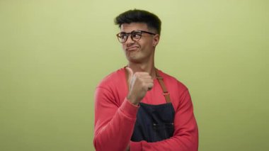 Gözlüklü genç adam sarı arka planda güvenle başparmak ucunda, rahat ve cana yakın bir tavır sergiliyor..