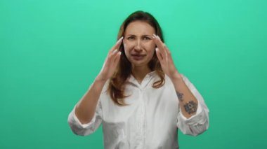 Genç bir kadın, güçlü duygular ve net vücut dili aktararak, canlı yeşil bir arka plana karşı ellerini kullanarak reddediyor..