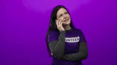 Akıllı telefondan konuşan gönüllü tişört esmer esmer arka plan. Kadın iletişimi, izole edilmiş açık hava insanı. Neşeli bir geçmişi var..