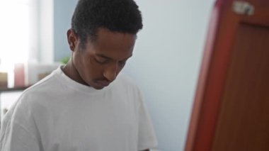 Kaplıca odasında beyaz gömlek giyen genç bir adam, aynaya yansıyan yumuşak ışıklandırma, dingin bir sağIık atmosferi yaratıyor..