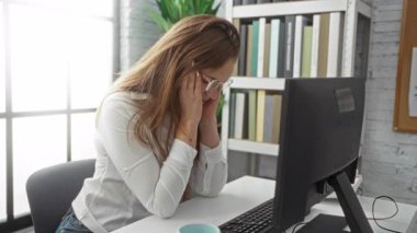 Ofisteki kadın, bilgisayarını kitaplarla ve bitki örtüsüyle çevrili bir şekilde masada otururken stresli hissediyor. Dul eşinin düşünceli ifadesinin yanında doğal ışık, düşünceyi yansıtıyor.