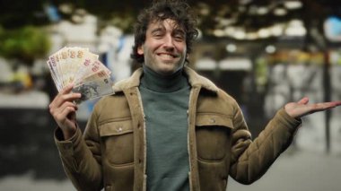 İspanyol adam elinde Türk lirası banknotlar tutarken gülümsüyor. Canlı bir şehir manzarası yakalıyor. Hoş bir jestle..