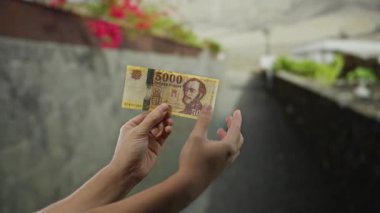 Bir şehir caddesinde elinde Macar banknotları tutan bir adam yeşil ve beton çevresi olan bir şehir merkezinde para gösteriyor..