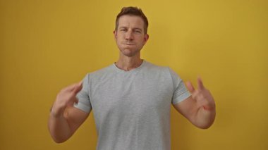 Genç adam izole edilmiş sarı arka planda komik bir jest yapıyor, gülüşünü işaret ederek, neşeli bir ifade ve neşeli bir mizah anı yakalıyor..