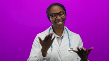 Pembe arka planda steteskopla gülümseyen kadın doktor, sağlık sektöründeki profesyonelliği vurguladı..