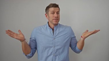 Kendine güvenen mavi gömlekli genç bir adam, izole edilmiş beyaz bir arka plana karşı duruyor, modern gündelik tarzda ve rahat bir tavırla..