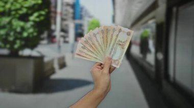 Birleşik Arap Emirlikleri 'ni elinde tutan adam açık havada güneşli bir şehir caddesinde kirli şehir zeminine karşı para birimi değeri gösteriyor..