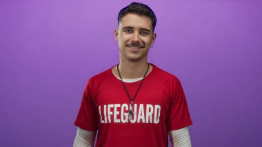 Kırmızı tişörtlü genç İspanyol cankurtaran izole edilmiş mor arka plan duvarına karşı duruyor.