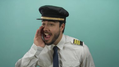 Mavi arka planda bağıran İspanyol üniformalı genç adam iletişim ya da talimatları işaret ediyor.