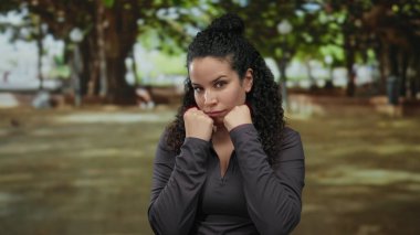 Açık hava parkında egzersiz yapan bir kadın odaklanmış ifadeyle ağaçların gölgesinde doğa ile çevrili sakin bir ortamda azim ve güç gösteriyor..