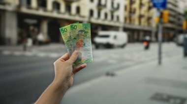 Şehir caddesinde elinde İsviçre frangı banknotları tutan adam açık hava ekonomisini ve finansmanı vurguluyor..