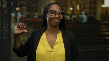 Sarı tişörtlü ve gözlüklü kadın şehir sokaklarında duygularını ifade ediyor ve arka planda insanlar var..