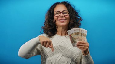 Elinde mavi arka planda Rus rublesi tutan gülümseyen bir kadın orta yaş yaşam tarzında finans, zenginlik ve para odaklarını gösteriyor..