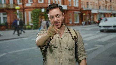 Sokakta sakallı ve sırt çantalı genç bir adam, canlı bir şehir ortamında turist enerjisi somutlaştırıyor tuğla binalar ve bulanık yaya geçmişi ile.