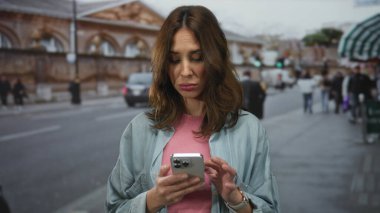 Yoğun şehir caddesinde akıllı telefon kullanan bir kadın, şehir ortamında mobil teknolojiyle meşgul olan genç İspanyol kadınları yakalıyor..