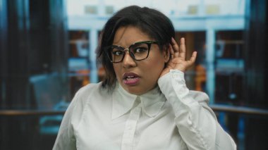 Otelde gözlüklü bir kadın. Kulağından kulağa dikkatle dinliyor. Meraklı profesyonel bir ortam olduğunu gösteriyor.