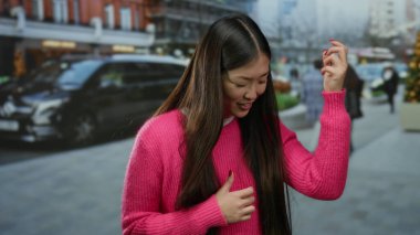 Şehirde canlı pembe süveterle gitar hareketlerini taklit eden, geçmişi bulanık bir kadın.