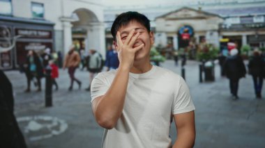 Kalabalık bir caddede gülen genç bir adam ve parlak bir günde arka planda yürüyen insanlar.