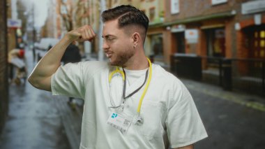 Sakallı ve steteskoplu beyaz önlüklü, açık hava güvenini gösteren beyaz önlüklü, şehrin arka planında gururla kolunu esnetiyor..