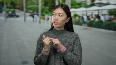 Şehir sokaklarında gezen, gri süveter giyen, şehir yaşamını ve modasını Asya kültürünün ve tarzının bir karışımıyla sergileyen bir kadın..