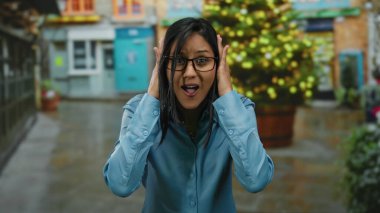 Mavi gömlekli bir kadın neşeli bir şehir sokağında neşeli bir şekilde jest yapıyor..