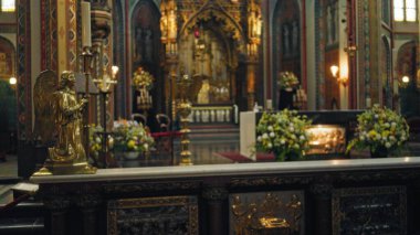 Altın melek heykeli bulanık, süslü bir kilise içini karmaşık kemerler ve çiçek düzenlemeleri ile süsler, katolik kutsallığı ve huzur dolu bir ortam yakalar..