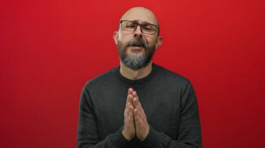 Kel, sakallı ve gözlüklü bir adam koyu renk bir süveter giyer ve stüdyoya kapanır..