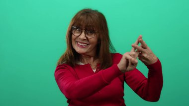 Kırmızı kazaklı kadın yeşil arka planda parmakları olan bir etiket işareti yapıyor.