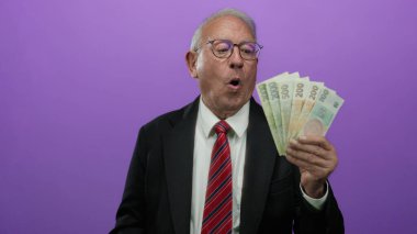 Takım elbiseli üst düzey bir adam elinde Czech Koruna banknotlarını mor arka planda tutuyor..