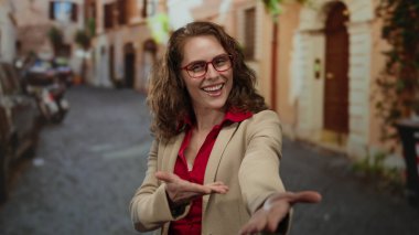 Büyüleyici bir şehir caddesinde elini uzatırken gülümseyen bir kadın, mutluluk ve kendine güven yayıyor canlı giyiniyor ve şehir arkaplanı.