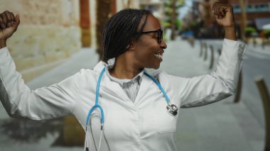 Şehrin arka planında steteskop ve gözlük takarak güvenle gülümseyen kadın doktor. Tarihi mimari ve ağaçlar sağlık merkezini yakalıyor.