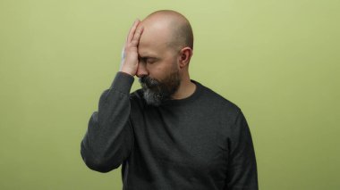 Sakallı ve dövmeli kel bir adam. Yüzü izole edilmiş sarı arka planda. Duygularını aktarıyor.