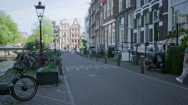 Antika binalar, bisikletler ve yeşilliklerin yer aldığı kentsel cazibeyi berrak gökyüzünün altında sakin bir atmosferle yakalayan amalar..