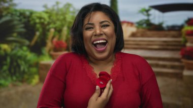 Parktaki kadın neşeyle yüzük kutusunu tutuyor. Açık havada evlenme teklif ediyor. Latince artı boyut mutlu nişanlı kadın..