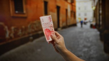 Kentsel bir sokakta el ele tutuşan Tayvan banknotları, iş ve seyahat odaklı yatırım ve finansmanı sembolize ediyor.