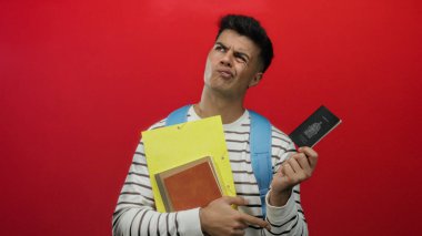 Kanada pasaportlu, çizgili tişörtlü, kırmızı arka planda sarı klasörlü seyahat ve kimlik kavramlarını tasvir eden bir adam..