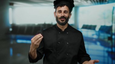 İspanyol şef sakallı. Havaalanı Terminali 1 'de beklenmedik bir seyahat ayarında neşeli ve kendine güvenen bir jest yapıyor..