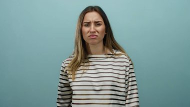 Sarı saçlı ve çizgili tişörtlü genç bir kadın. Katı mavi arka plan duvarına karşı rahatsız edici bir ifade sergiliyor. Canlı bir duygusal izlenim yaratıyor..