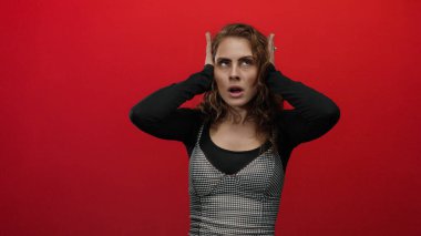 Çizgili elbiseli bir kadın gözlerini kırmızı arkaplanda kapalı tutarak stres ya da hayal kırıklığını ima ediyor.